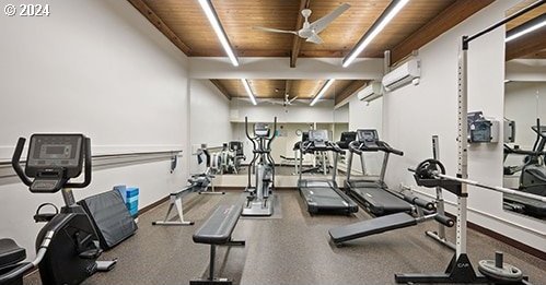 exercise room featuring a wall mounted air conditioner, ceiling fan, and wooden ceiling