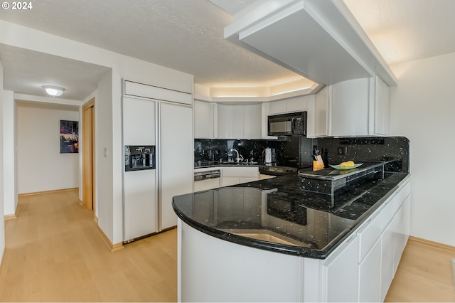 kitchen featuring white cabinets, white dishwasher, light hardwood / wood-style flooring, decorative backsplash, and paneled refrigerator