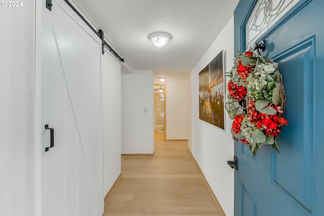 hallway with a barn door and light hardwood / wood-style floors