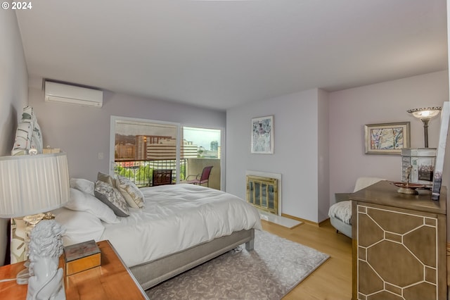 bedroom with an AC wall unit, access to exterior, and light hardwood / wood-style flooring