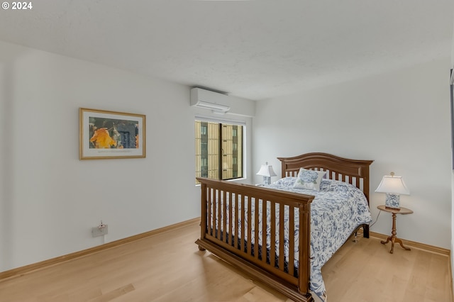 bedroom with light hardwood / wood-style floors and a wall mounted AC