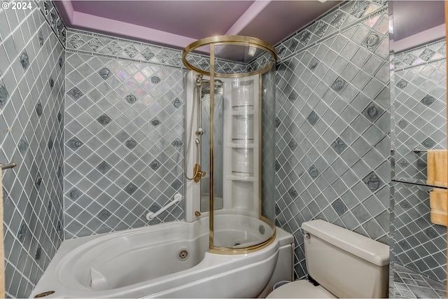 bathroom featuring tiled shower / bath combo, toilet, and tile walls