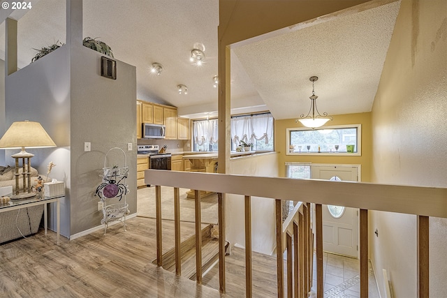 interior space featuring lofted ceiling, light hardwood / wood-style flooring, and a textured ceiling