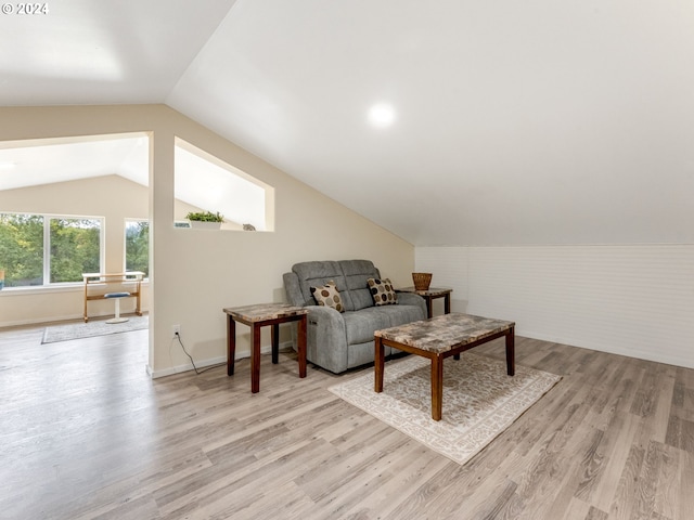 sitting room with light wood-type flooring, vaulted ceiling, and baseboards