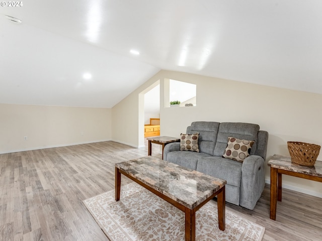 living area featuring light wood-type flooring, lofted ceiling, and baseboards