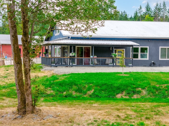 back of property featuring covered porch, metal roof, and a lawn