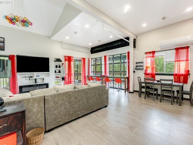 living room featuring a wall mounted AC, light hardwood / wood-style flooring, and a healthy amount of sunlight