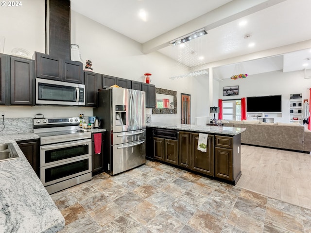 kitchen featuring appliances with stainless steel finishes, open floor plan, light stone countertops, high vaulted ceiling, and a peninsula