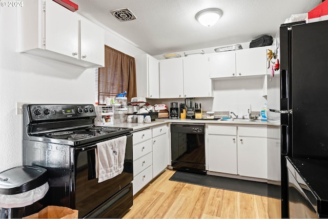 kitchen featuring light wood-type flooring, a textured ceiling, sink, white cabinets, and black appliances