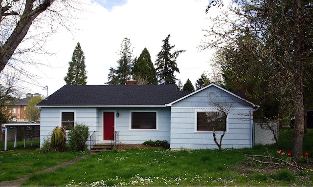 ranch-style home with a front lawn, a chimney, entry steps, and roof with shingles