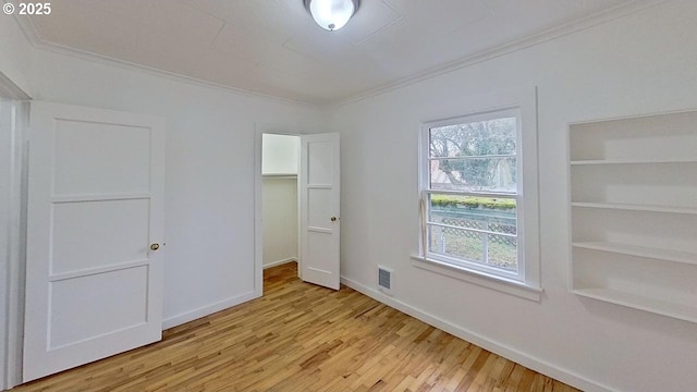 unfurnished bedroom featuring a closet, ornamental molding, baseboards, and wood finished floors