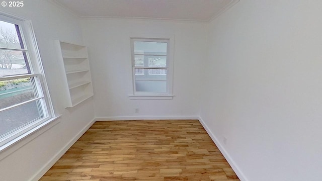 unfurnished room with built in shelves, light wood-type flooring, and ornamental molding