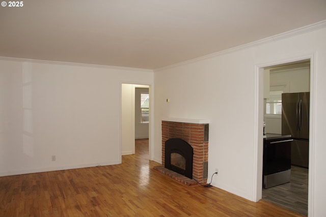 unfurnished living room featuring baseboards, a fireplace, crown molding, and wood finished floors
