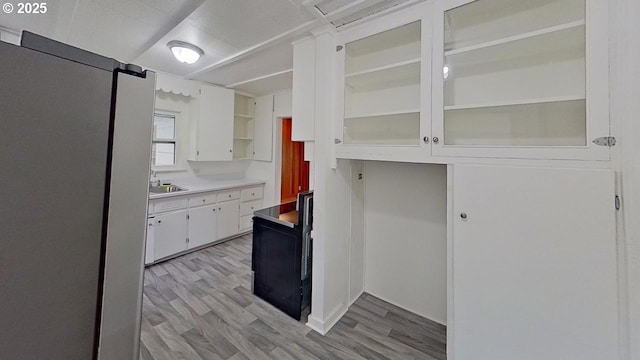 kitchen featuring a sink, open shelves, freestanding refrigerator, white cabinetry, and light wood-style flooring