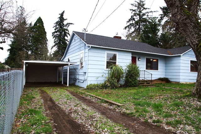 view of front facade featuring a detached carport, driveway, fence, and a chimney