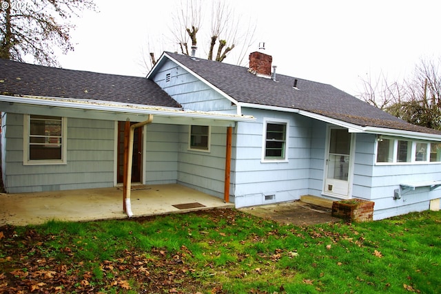 back of property featuring a lawn, a chimney, a shingled roof, and a patio