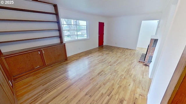 unfurnished living room featuring crown molding and light wood finished floors