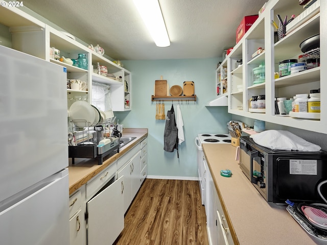 kitchen with white appliances, a textured ceiling, white cabinetry, and hardwood / wood-style floors