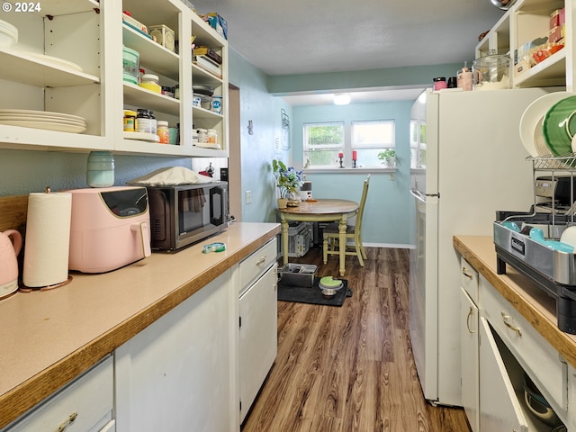 kitchen featuring white cabinets, white refrigerator, and hardwood / wood-style floors