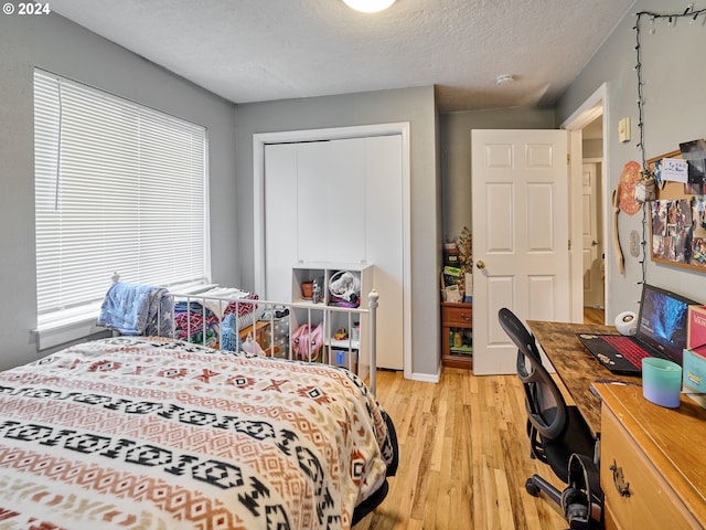 bedroom featuring a closet, a textured ceiling, and light wood-type flooring