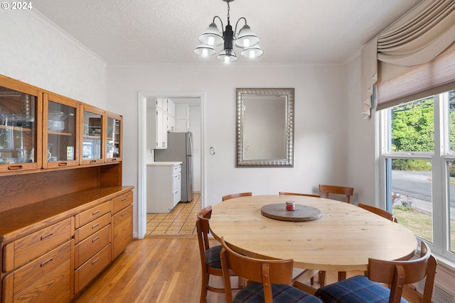 dining room with light hardwood / wood-style floors, a notable chandelier, ornamental molding, and a textured ceiling