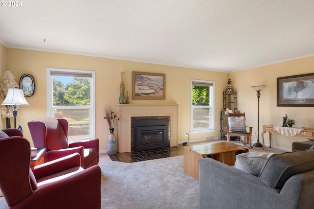 carpeted living room featuring a tiled fireplace, a textured ceiling, ornamental molding, and plenty of natural light