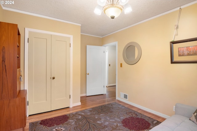 interior space with a closet, light hardwood / wood-style floors, ornamental molding, and a textured ceiling