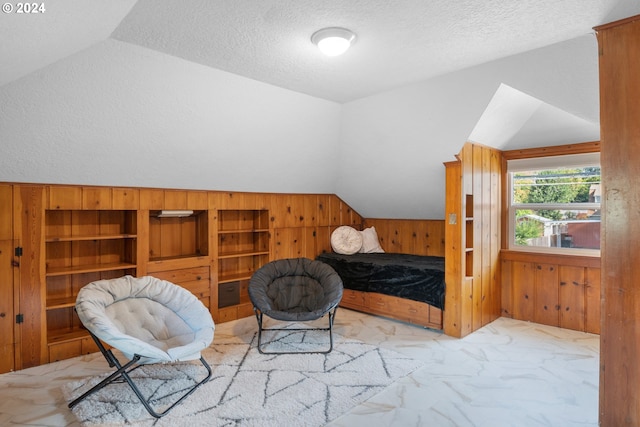 sitting room with vaulted ceiling, a textured ceiling, and wood walls