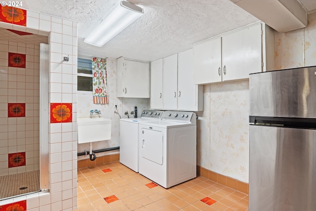 laundry area with sink, washer and dryer, cabinets, and light tile patterned floors