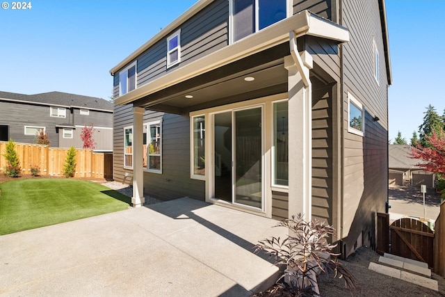 back of house with a patio area and a lawn