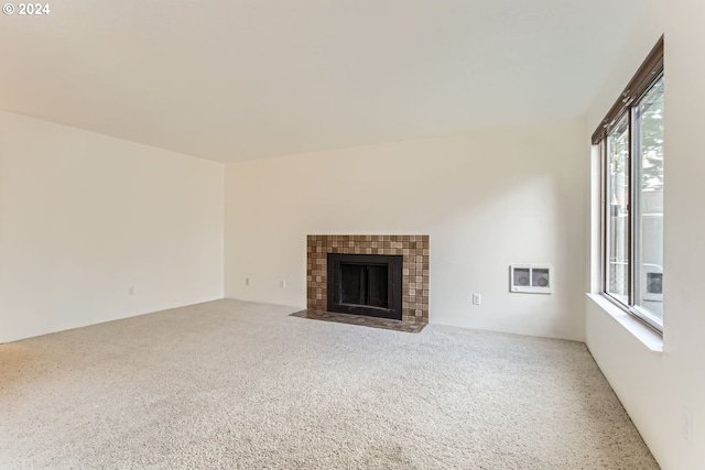 unfurnished living room featuring carpet and a tiled fireplace