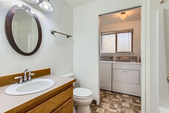 bathroom featuring vanity, washing machine and dryer, and toilet