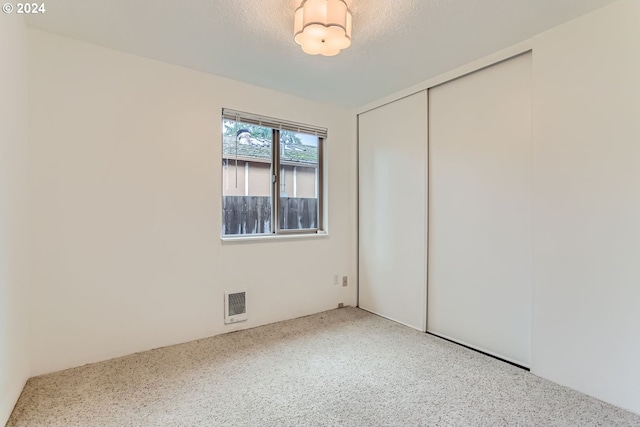 unfurnished bedroom featuring a textured ceiling and a closet