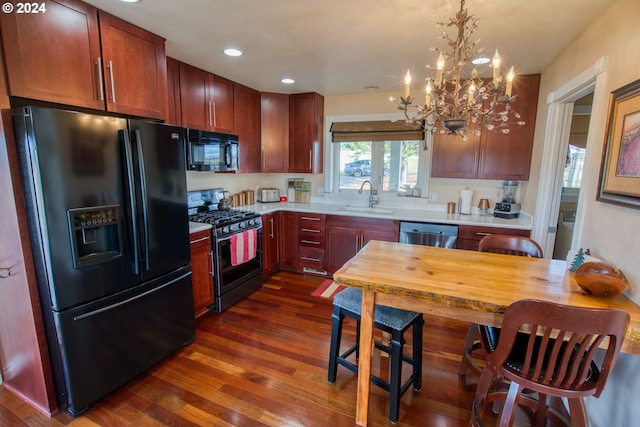 kitchen with sink, hanging light fixtures, dark wood-type flooring, an inviting chandelier, and black appliances