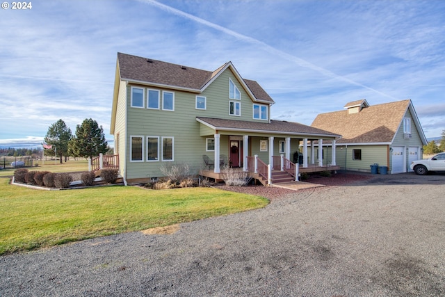 view of front of home featuring a porch, a garage, an outbuilding, and a front lawn