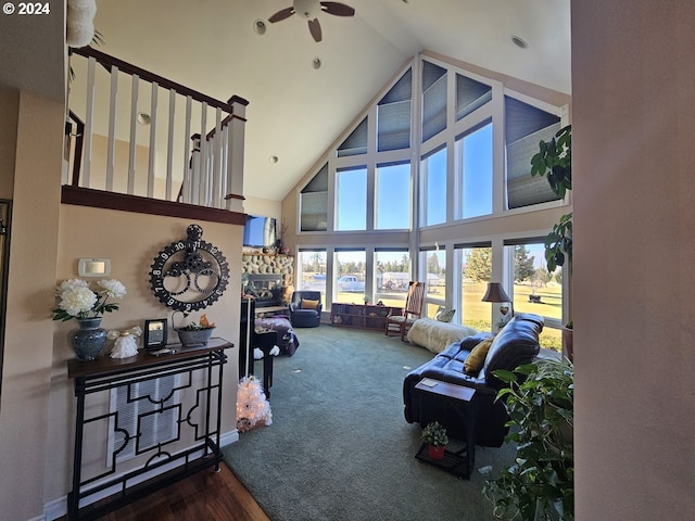 living room with carpet, ceiling fan, a fireplace, and a high ceiling