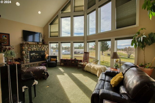 living room featuring carpet flooring, high vaulted ceiling, and a stone fireplace