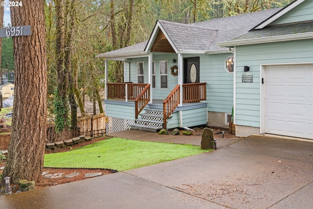 ranch-style house with covered porch, a shingled roof, and a garage