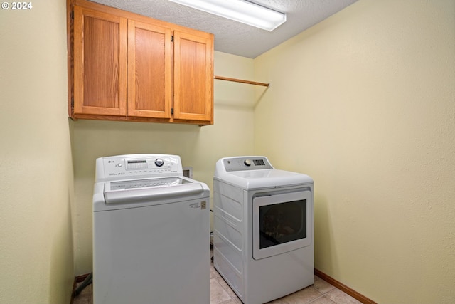 laundry area featuring cabinet space, washer and dryer, a textured ceiling, and baseboards