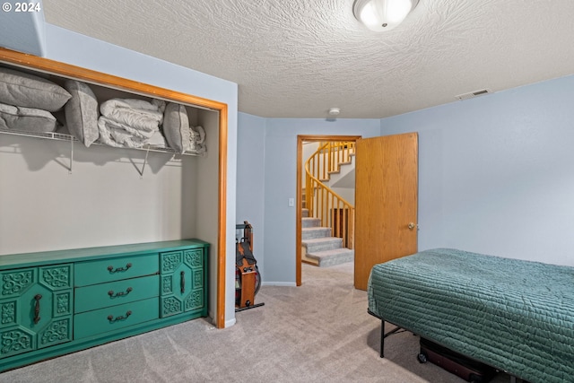 carpeted bedroom featuring baseboards, visible vents, and a textured ceiling