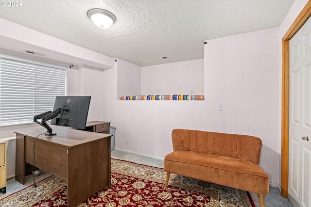 office area with baseboards, light colored carpet, visible vents, and a textured ceiling