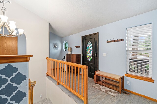 entrance foyer with an inviting chandelier, hardwood / wood-style floors, lofted ceiling, and a textured ceiling