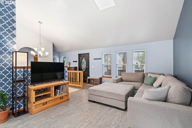 living area featuring a textured ceiling, lofted ceiling, wood finished floors, and a chandelier