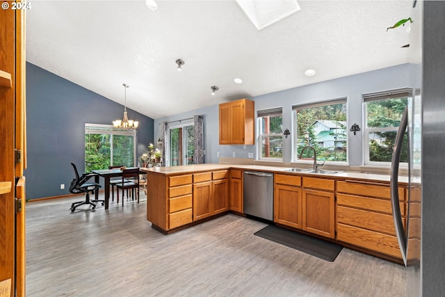 kitchen with a sink, light wood-style floors, appliances with stainless steel finishes, and a peninsula