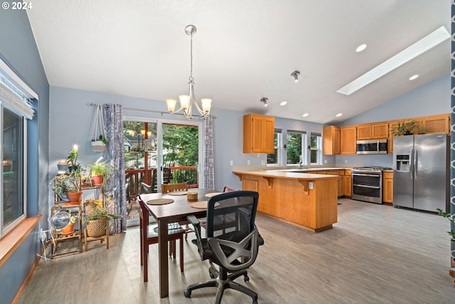 dining area featuring a wealth of natural light, vaulted ceiling with skylight, and light wood finished floors