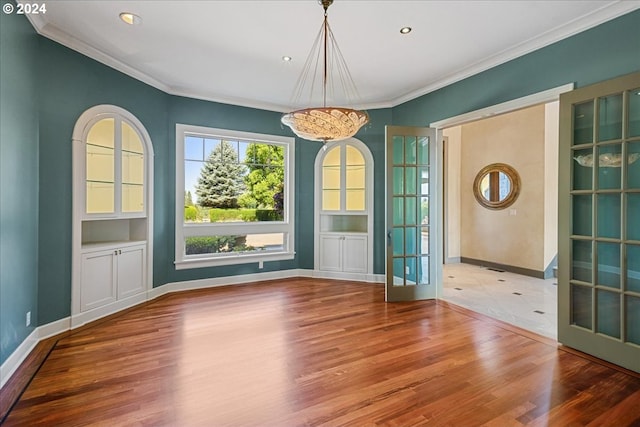 unfurnished dining area with a notable chandelier, french doors, crown molding, and hardwood / wood-style flooring