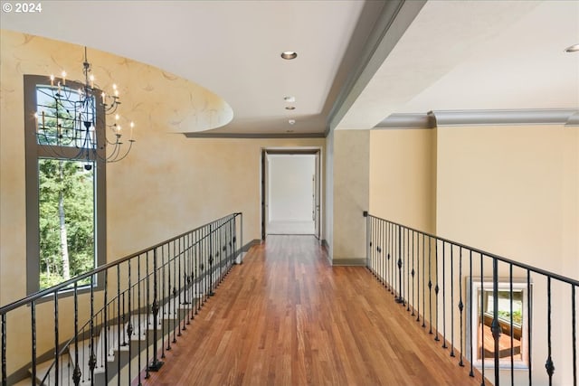 hallway with wood-type flooring, crown molding, and a notable chandelier