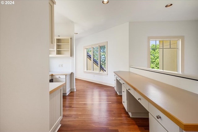 kitchen with built in desk, dark hardwood / wood-style flooring, and white cabinetry