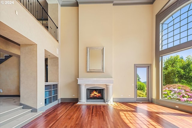 unfurnished living room featuring a towering ceiling, wood-type flooring, and plenty of natural light