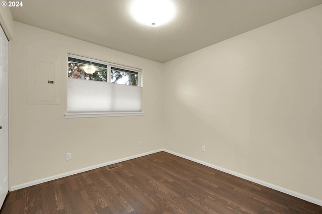 spare room featuring electric panel and dark hardwood / wood-style flooring